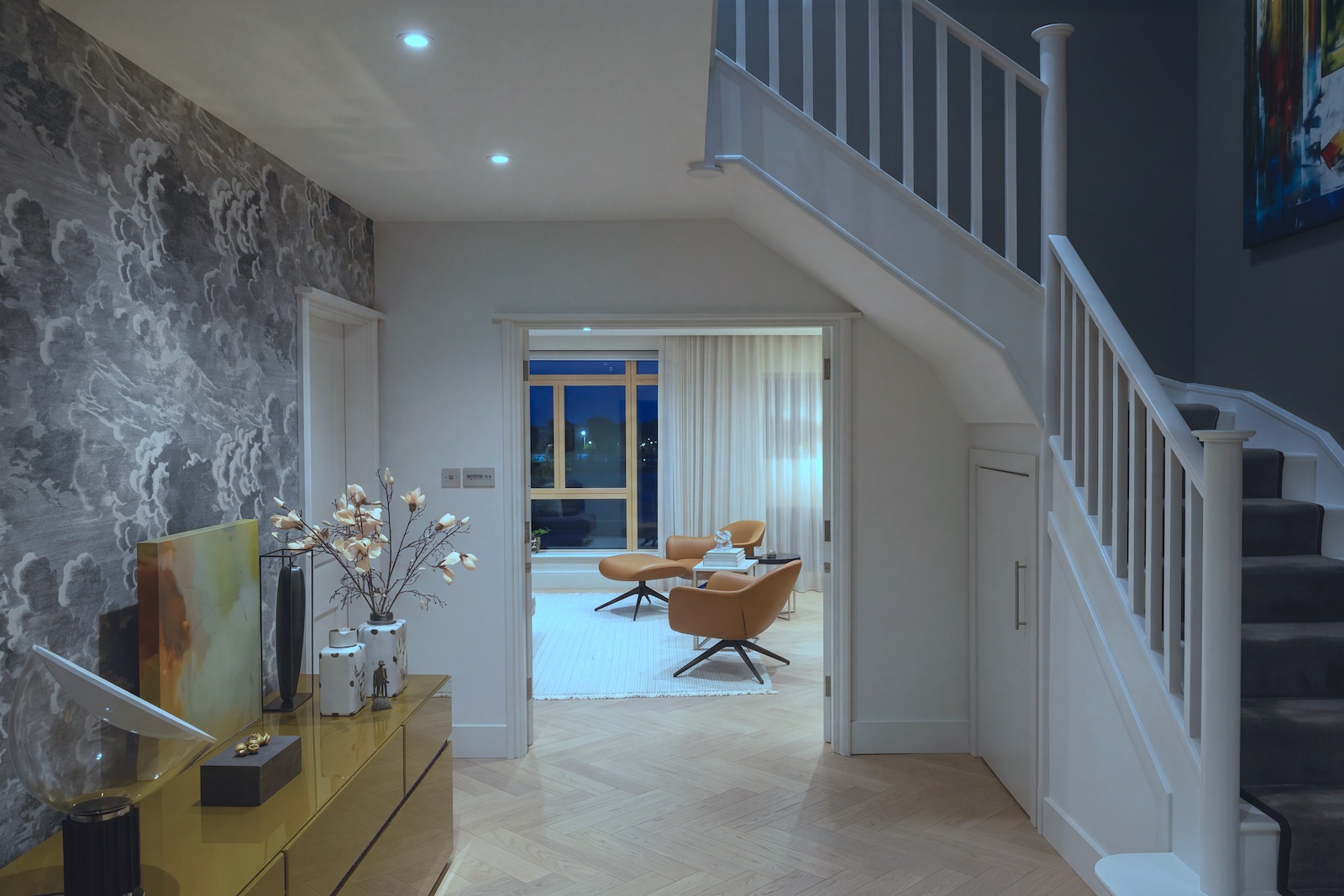 Modern hallway with mustard-yellow console table and cloud-patterned wallpaper, leading into a lounge with tan leather armchairs. Photography by Vanity Pix.